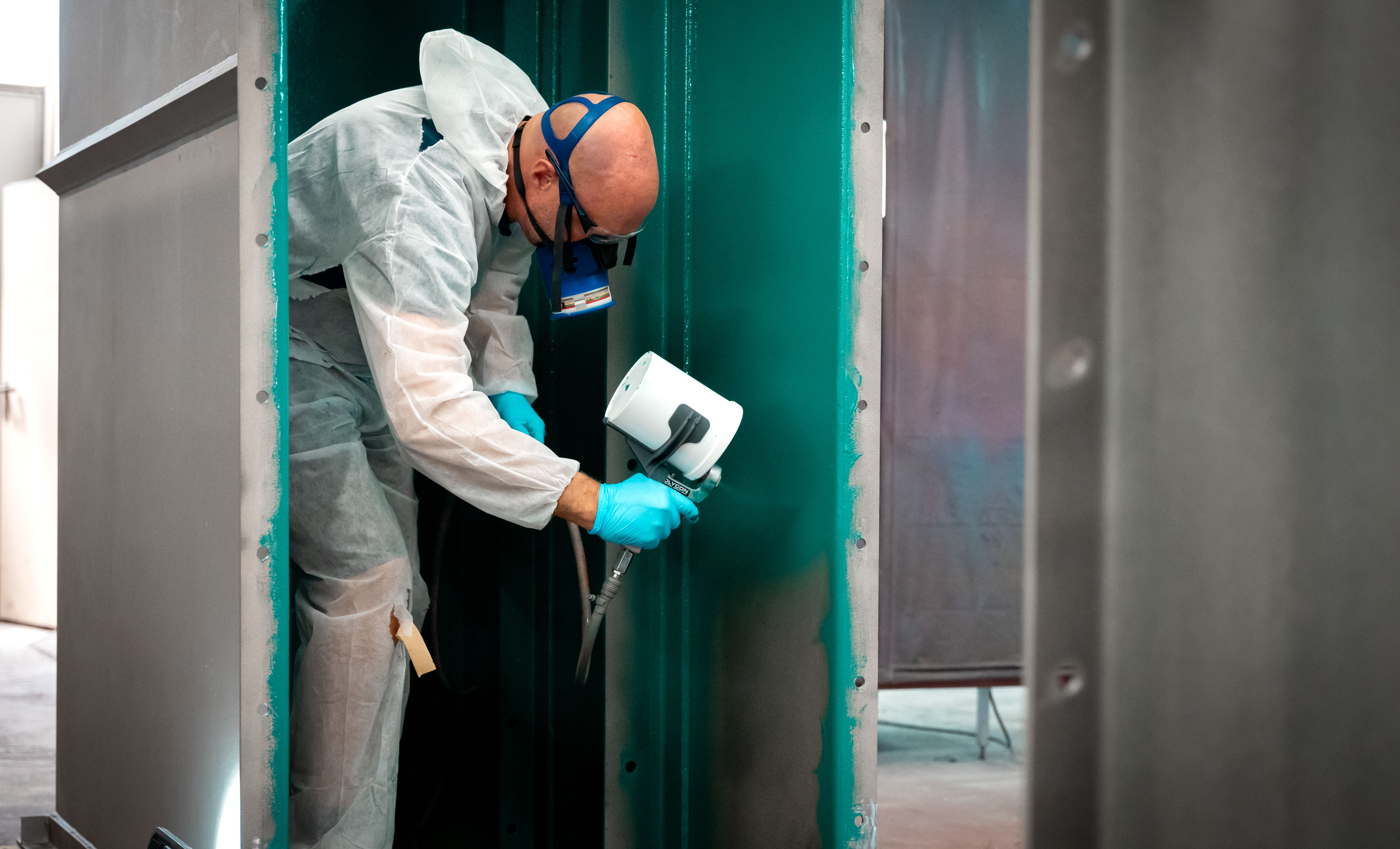 Un hombre con mascarilla pulveriza una capa de control verde